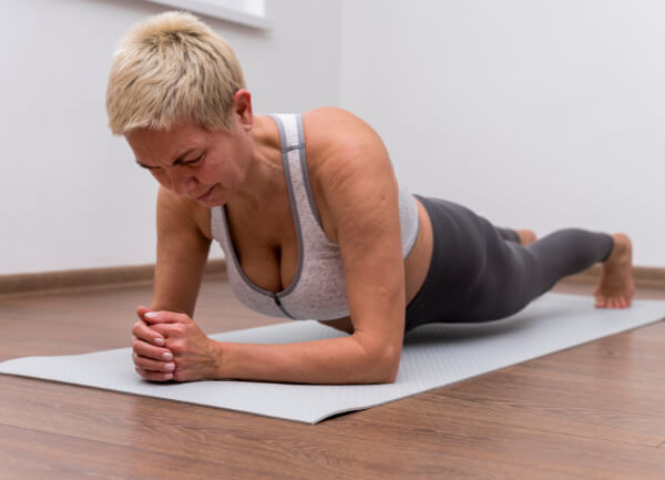 Femme de 50 ans qui pratique des exercices doux comme le gainage pour affiner son ventre
